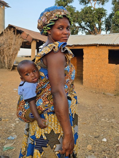 A woman carrying a child at Sanda Afohou Village, Togo 2026