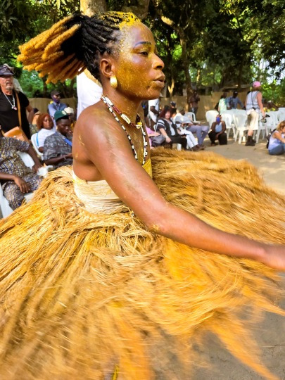 Woman dressed in raffia and yellow paste performing the Kokou spiritual dance at Vodun Days Festival in Ouidah, Benin 2026