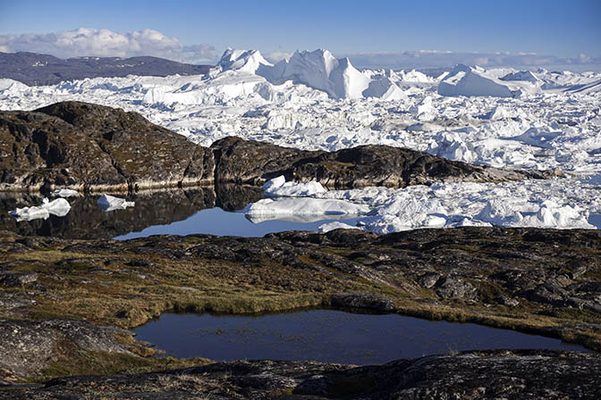 Floating ice in Ilulissat's Icefjord with blue puddles in the rocky ground, 2017